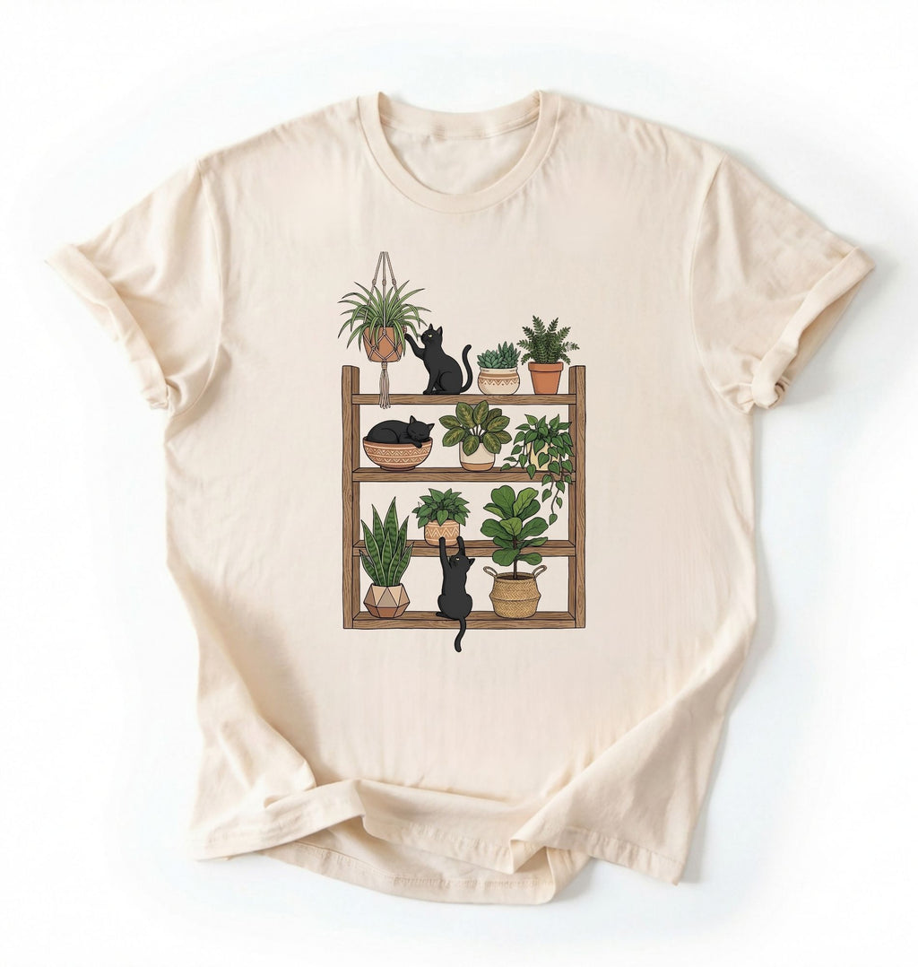 Flat lay of a Natural t-shirt featuring illustrated cats sitting and playing on a shelf of potted plants on a white background