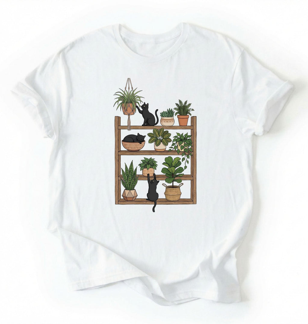 Flat lay of a white t-shirt featuring illustrated cats sitting and playing on a shelf of potted plants on a white background