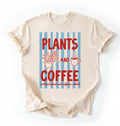 Flat lay of a Natural ivory t-shirt featuring plant illustrations and a coffee cup with text reading “Plants and Coffee.” with retro stripes plant lover gift white graphic tee for coffee drinker and houseplant enthusiast on a white background 