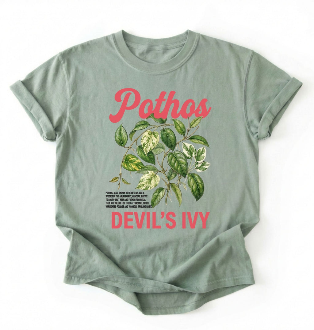 Flat lay of a sage t-shirt featuring a botanical leaf illustration of Pothos leaves with text reading “Pothos Devil’s Ivy” perfect gift for plant lovers and houseplant enthusiasts on white background 