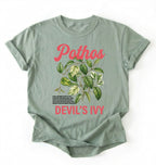 Flat lay of a sage t-shirt featuring a botanical leaf illustration of Pothos leaves with text reading “Pothos Devil’s Ivy” perfect gift for plant lovers and houseplant enthusiasts on white background 