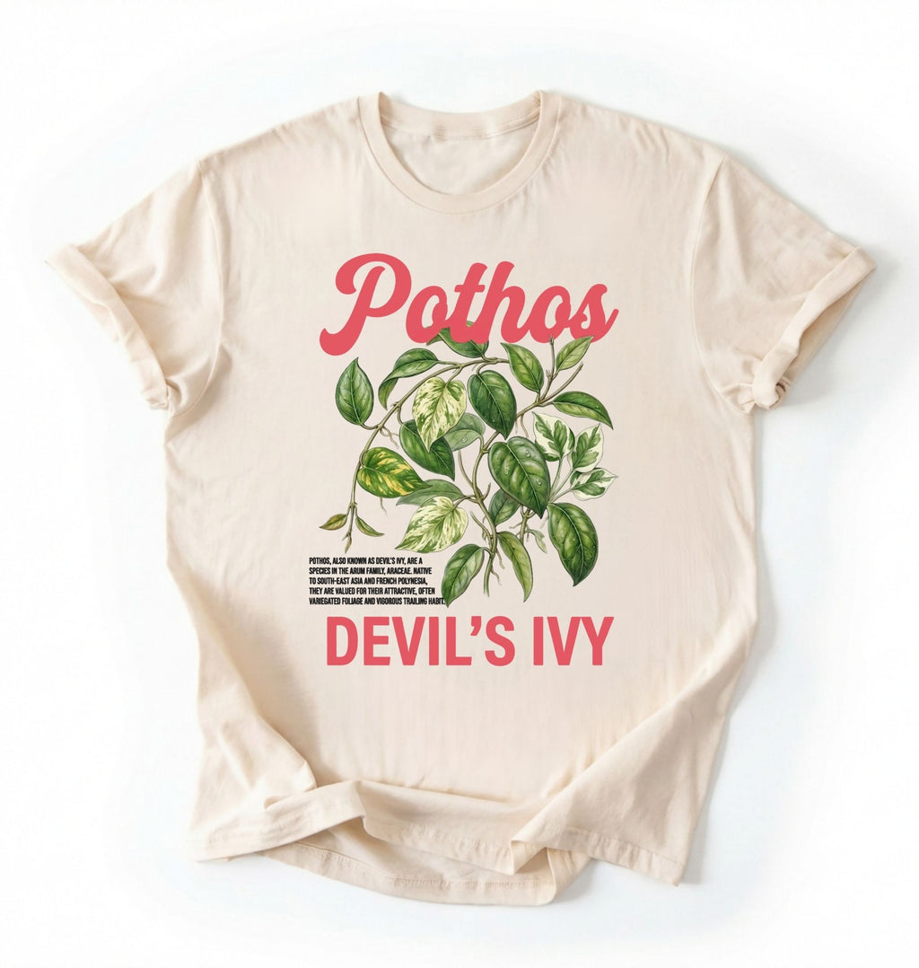 Flat lay of a natural t-shirt featuring a botanical leaf illustration of Pothos leaves with text reading “Pothos Devil’s Ivy” perfect gift for plant lovers and houseplant enthusiasts on white background 