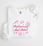 A white long-sleeve sweatshirt with a pink graphic that reads 'Professional Mess Maker' surrounded by baking-themed illustrations, laid flat on a white background.