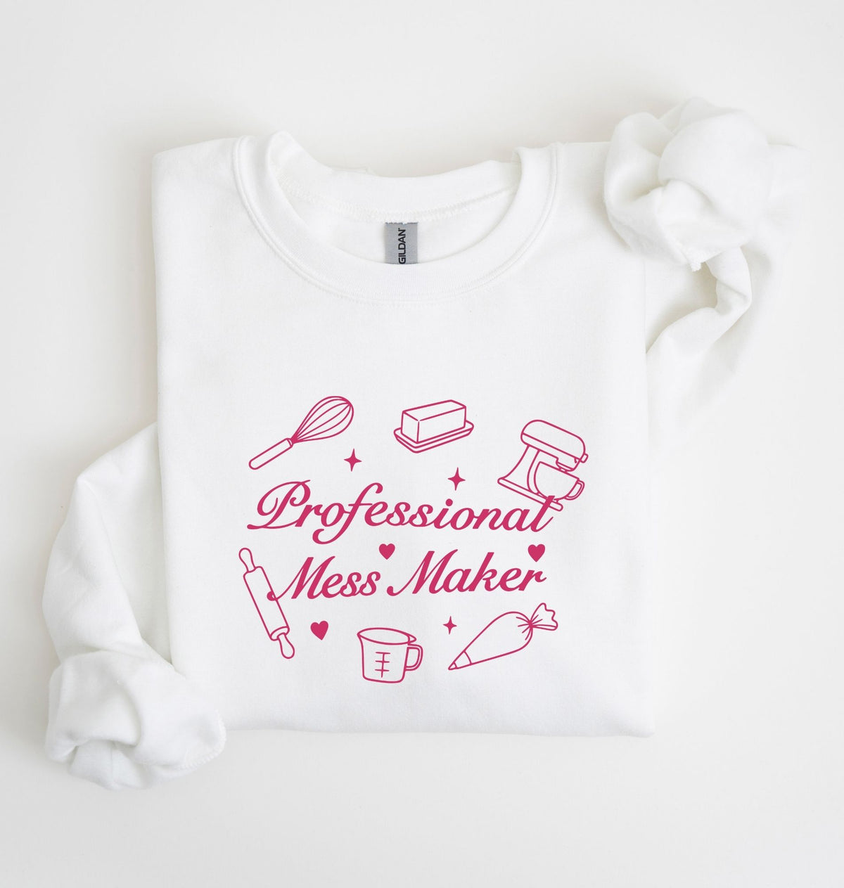 A white long-sleeve sweatshirt with a pink graphic that reads 'Professional Mess Maker' surrounded by baking-themed illustrations, laid flat on a white background.