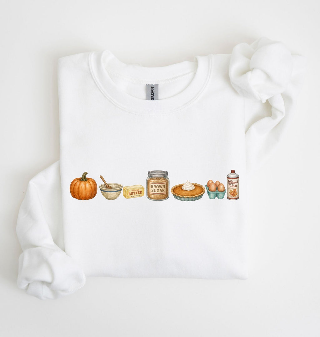 A white crewneck sweatshirt with a horizontal watercolor graphic of autumn baking elements, including a pumpkin, butter, brown sugar, pie, eggs, and cinnamon, displayed on a clean white background.