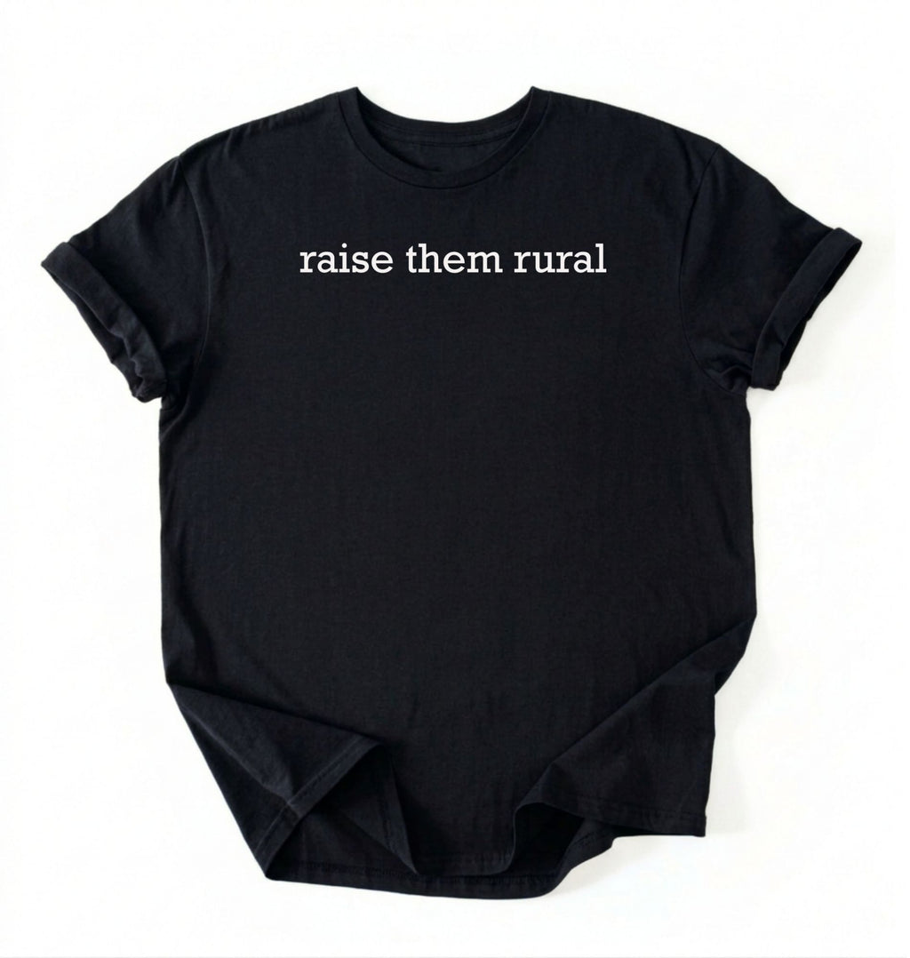 Flat lay of a Raise Them Rural country graphic shirt in black for farm families rural lifestyle and country living on a white background