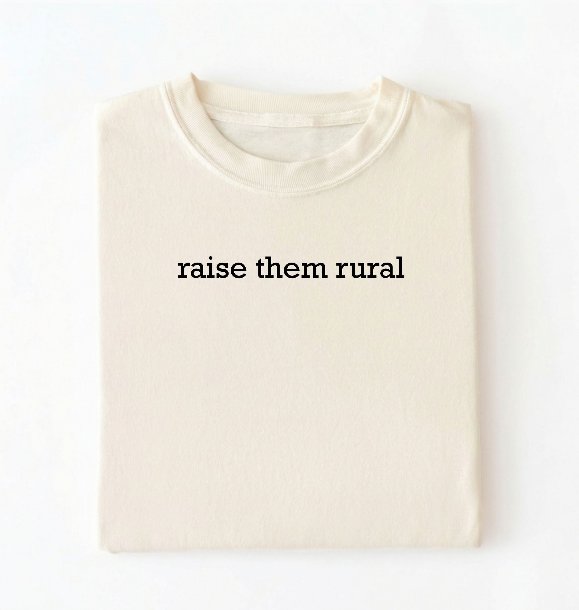 Flat lay of a Raise Them Rural country graphic shirt in ivory for farm families rural lifestyle and country living on a white background