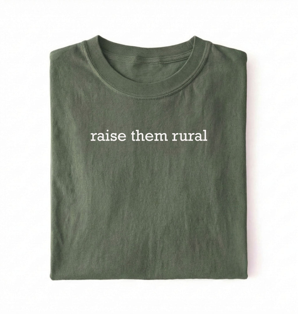 Flat lay of a Raise Them Rural country graphic shirt in green for farm families rural lifestyle and country living on a white background 