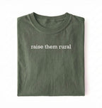 Flat lay of a Raise Them Rural country graphic shirt in green for farm families rural lifestyle and country living on a white background 