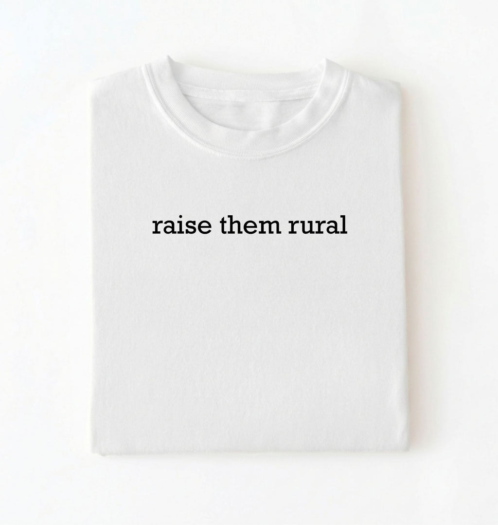 Flat lay of a Raise Them Rural country graphic shirt in white for farm families rural lifestyle and country living on a white background