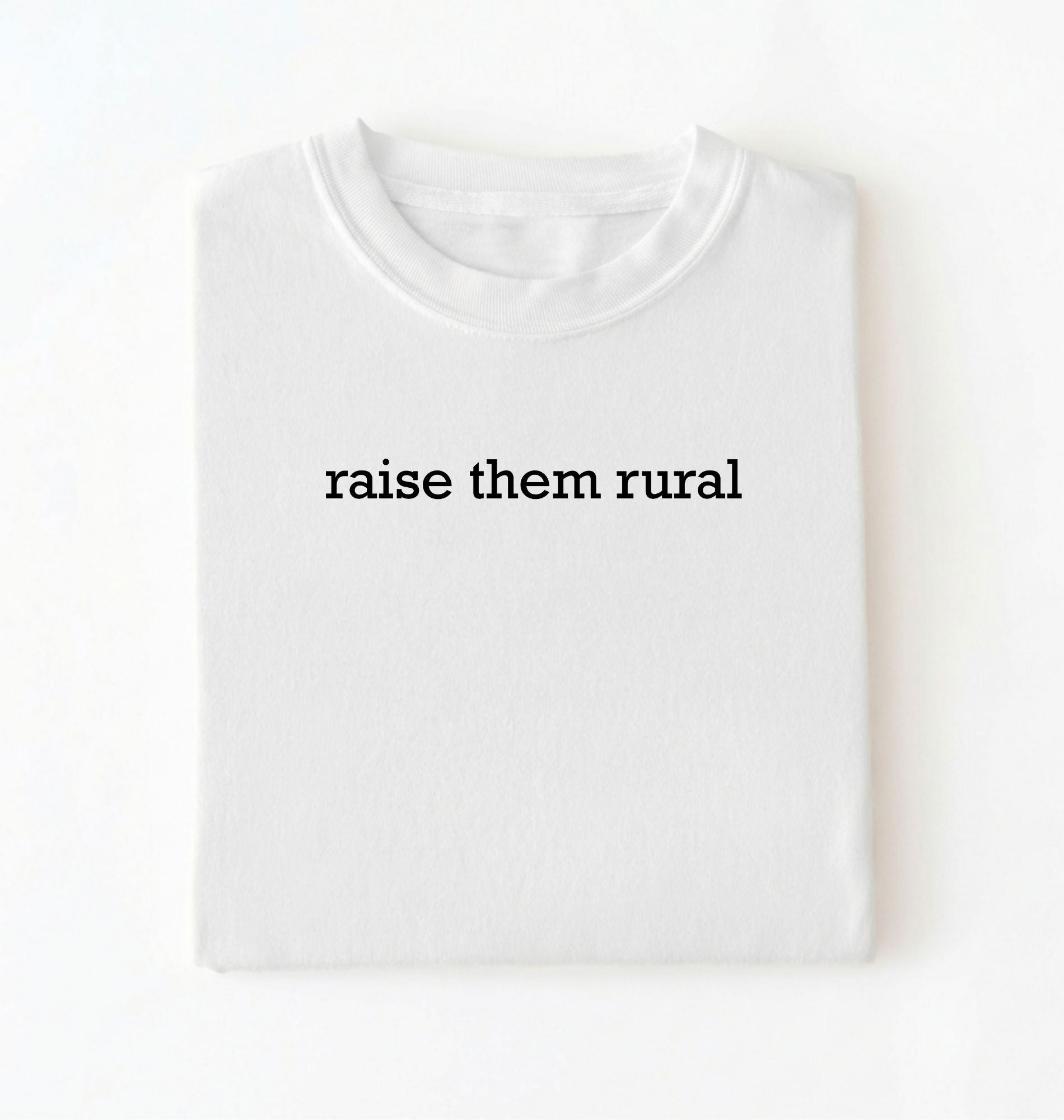 Flat lay of a Raise Them Rural country graphic shirt in white for farm families rural lifestyle and country living on a white background