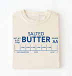 Flat lay of a ivory salted butter shirt funny baking t shirt foodie baker aesthetic gift on a white background 