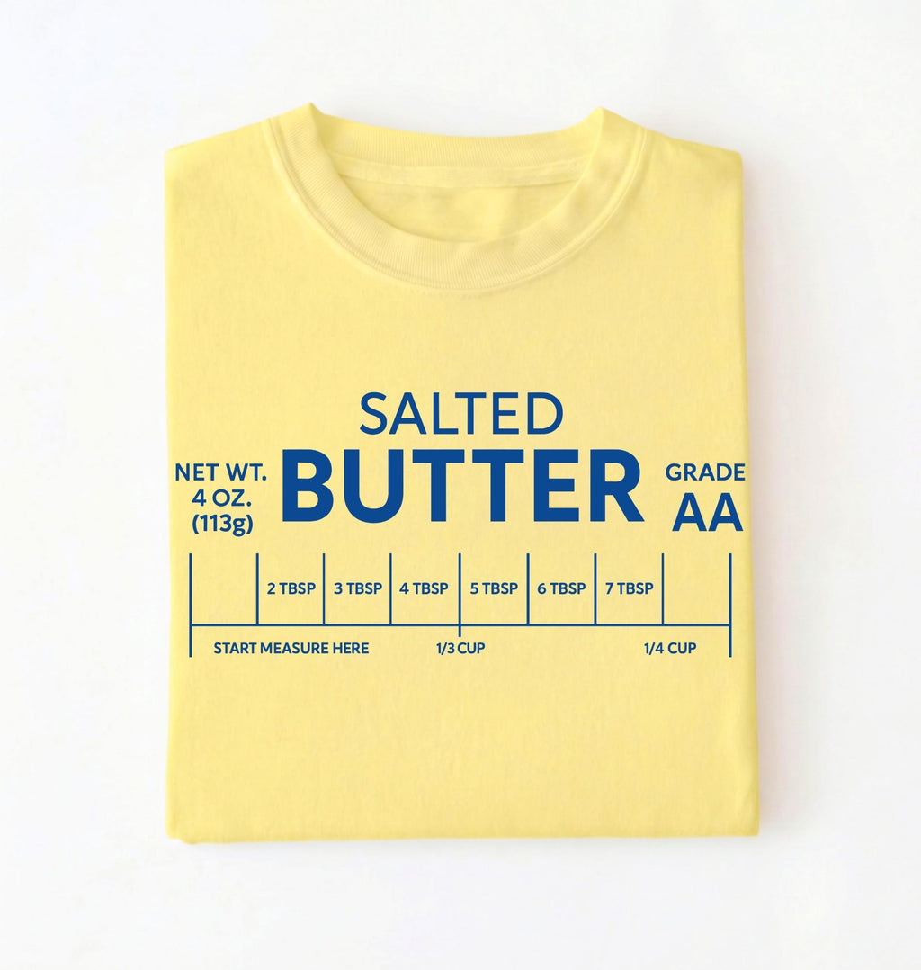 Flat lay of a cornsilk salted butter shirt yellow funny baking t shirt foodie baker aesthetic gift on a white background 