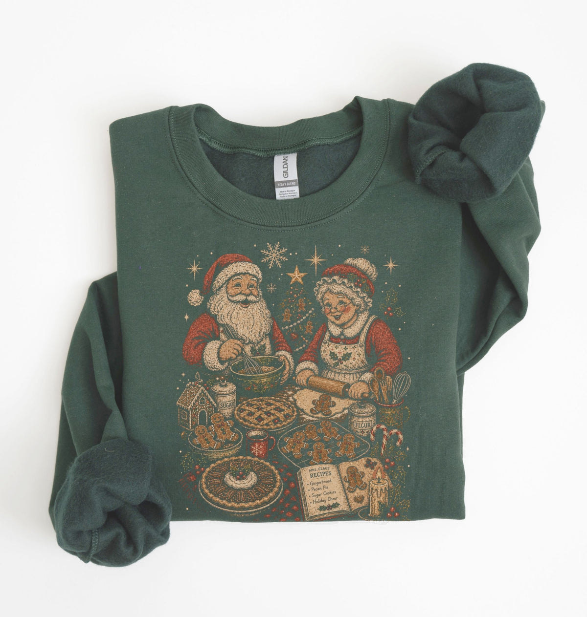 A dark green crewneck sweatshirt featuring a vintage-style Christmas graphic of Santa and Mrs. Claus baking cookies, styled flat on a white background with the cuffs folded up.