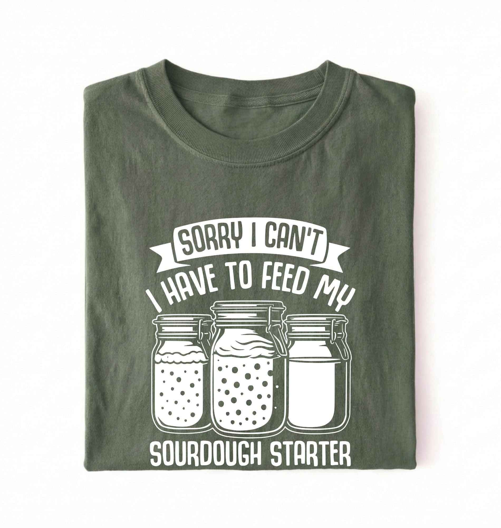 Flat lay of a green Sorry I Can't I Have to Feed My Sourdough Starter shirt with starter jar graphic on charcoal t-shirt on a white background 