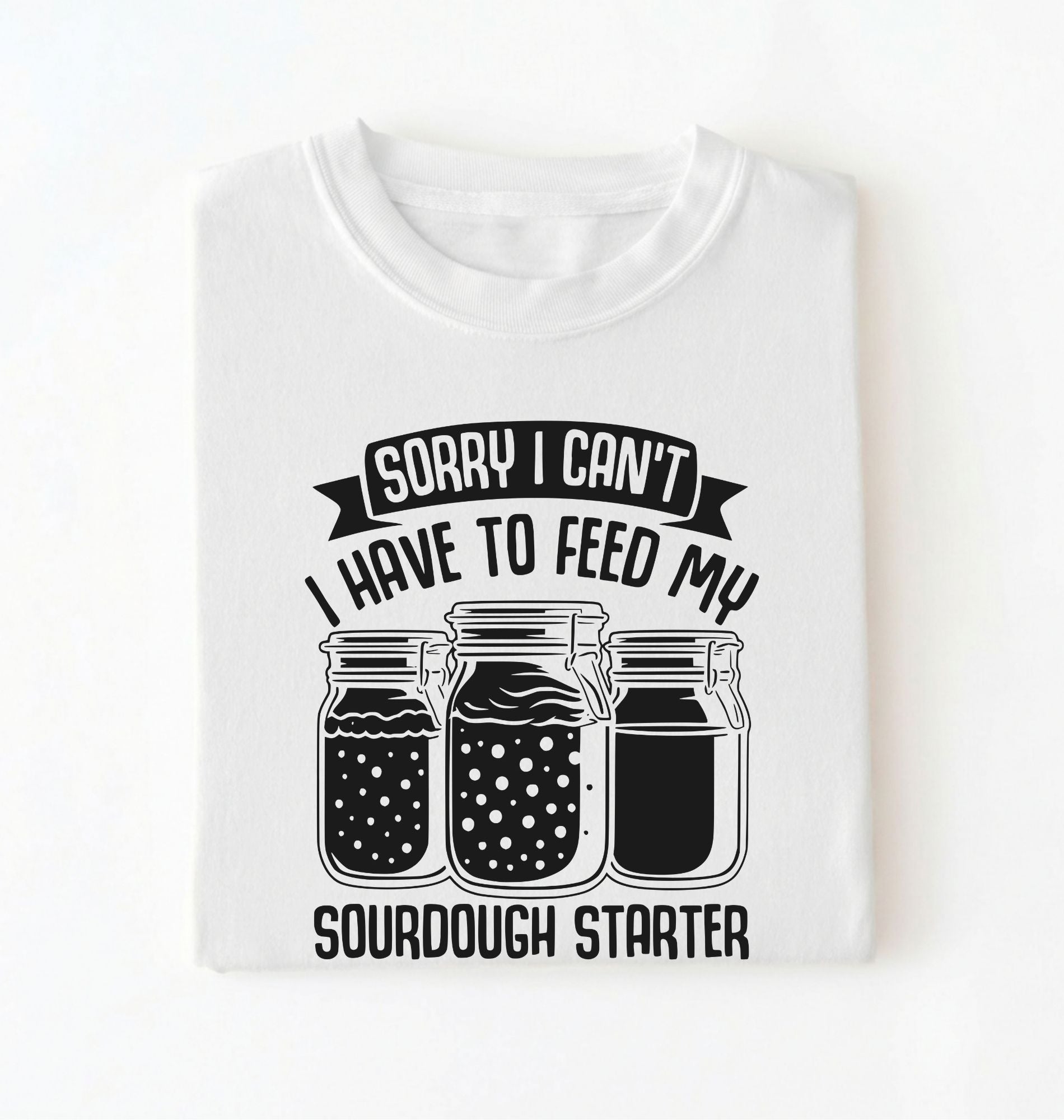 Flat lay of a white Sorry I Can't I Have to Feed My Sourdough Starter shirt with starter jar graphic on charcoal t-shirt on a white background 