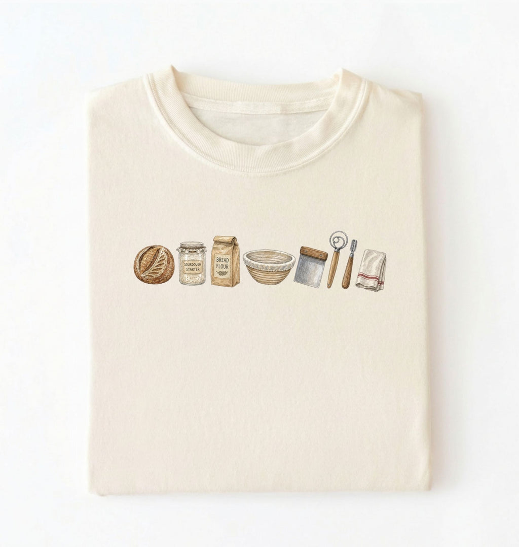 Flat lay of a ivory sourdough baking essentials shirt with starter flour dough bowl and bread making tools on a white background 
