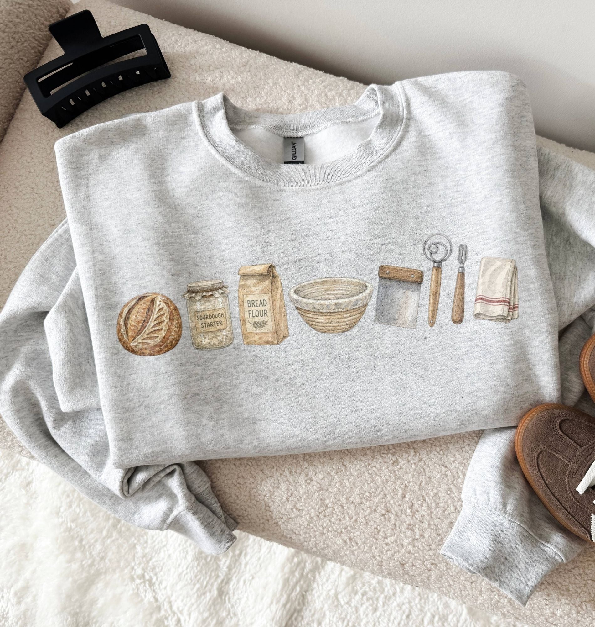 Gray sweatshirt with bread-themed illustrations on a textured surface