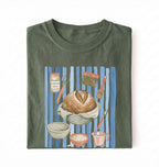 Flat lay of a green Sourdough baking tools shirt featuring artisan bread, starter jar, banneton, and baking supplies on a white background 