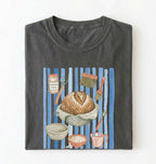 Flat lay of a charcoal Sourdough baking tools shirt featuring artisan bread, starter jar, banneton, and baking supplies on a white background 