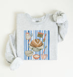 Flat lay of an ash Sourdough baking tools sweatshirt featuring artisan bread, starter jar, banneton, and baking supplies on a white background 