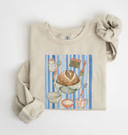 Flat lay of a sand Sourdough baking tools sweatshirt featuring artisan bread, starter jar, banneton, and baking supplies on a white background 