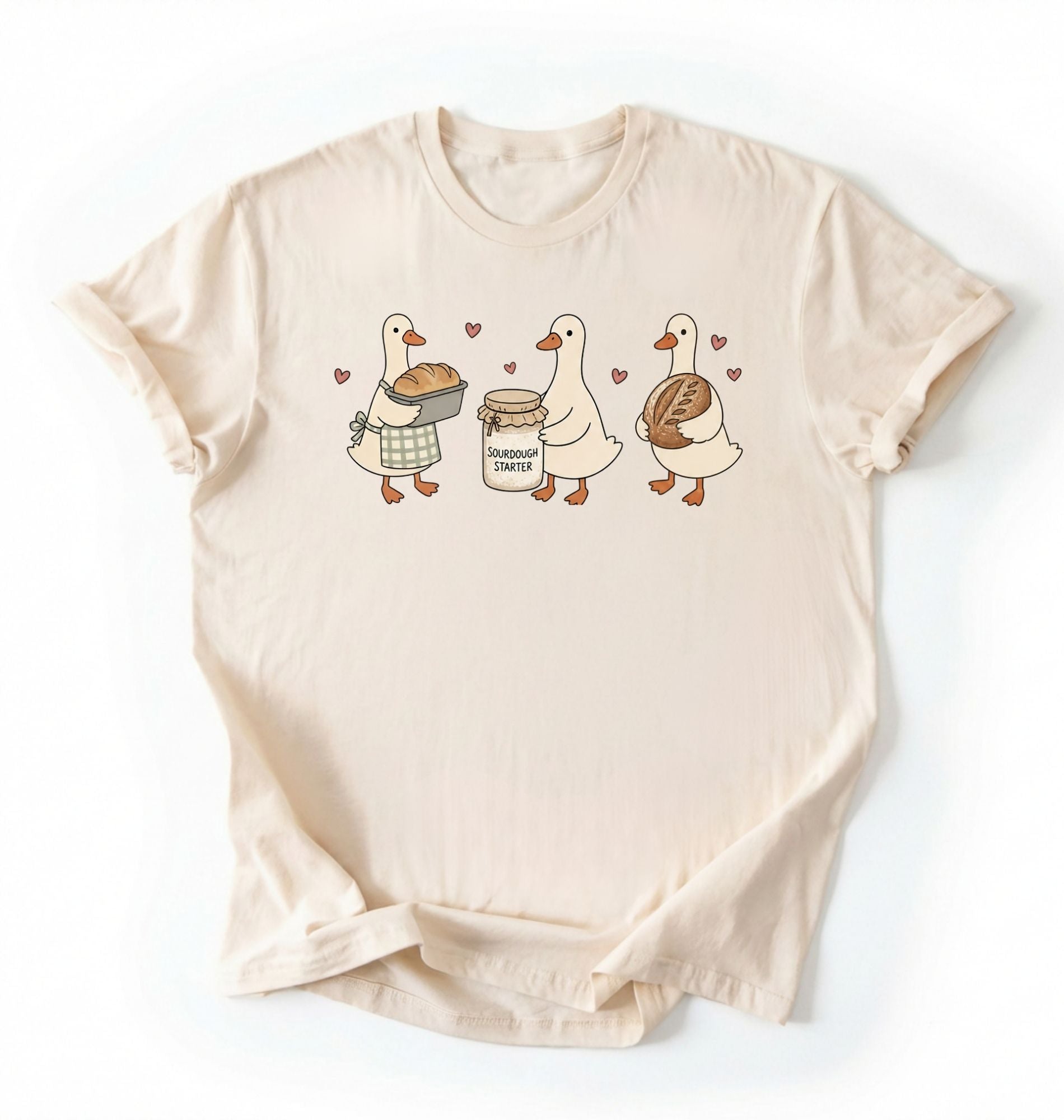 Flat lay of a cream Cute sourdough ducks graphic shirt featuring bread and sourdough starter design for bakers on a white background