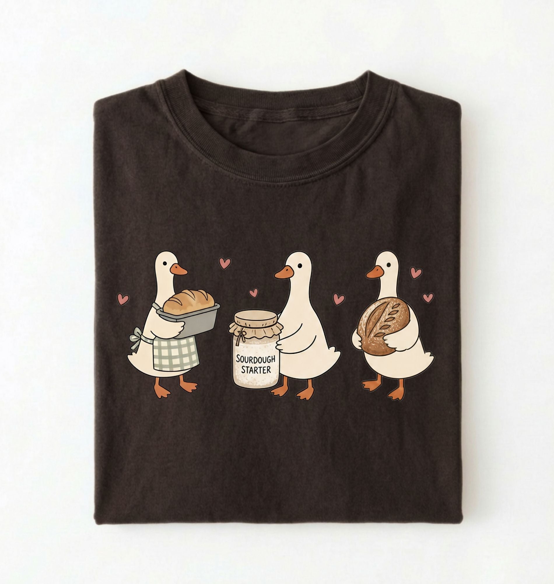 Flat lay of a Cute sourdough ducks graphic shirt featuring bread and sourdough starter design for bakers on a white background