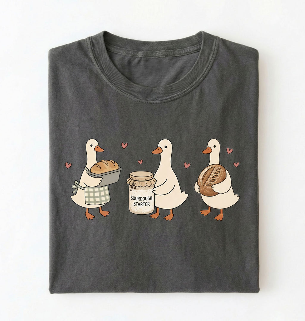 Flat lay of a gray Cute sourdough ducks graphic shirt featuring bread and sourdough starter design for bakers on a white background