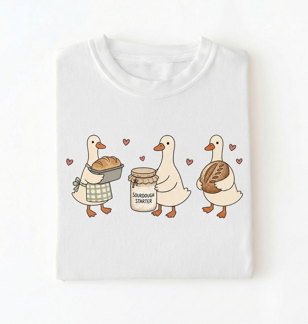 Flat lay of a white Cute sourdough ducks graphic shirt featuring bread and sourdough starter design for bakers on a white background