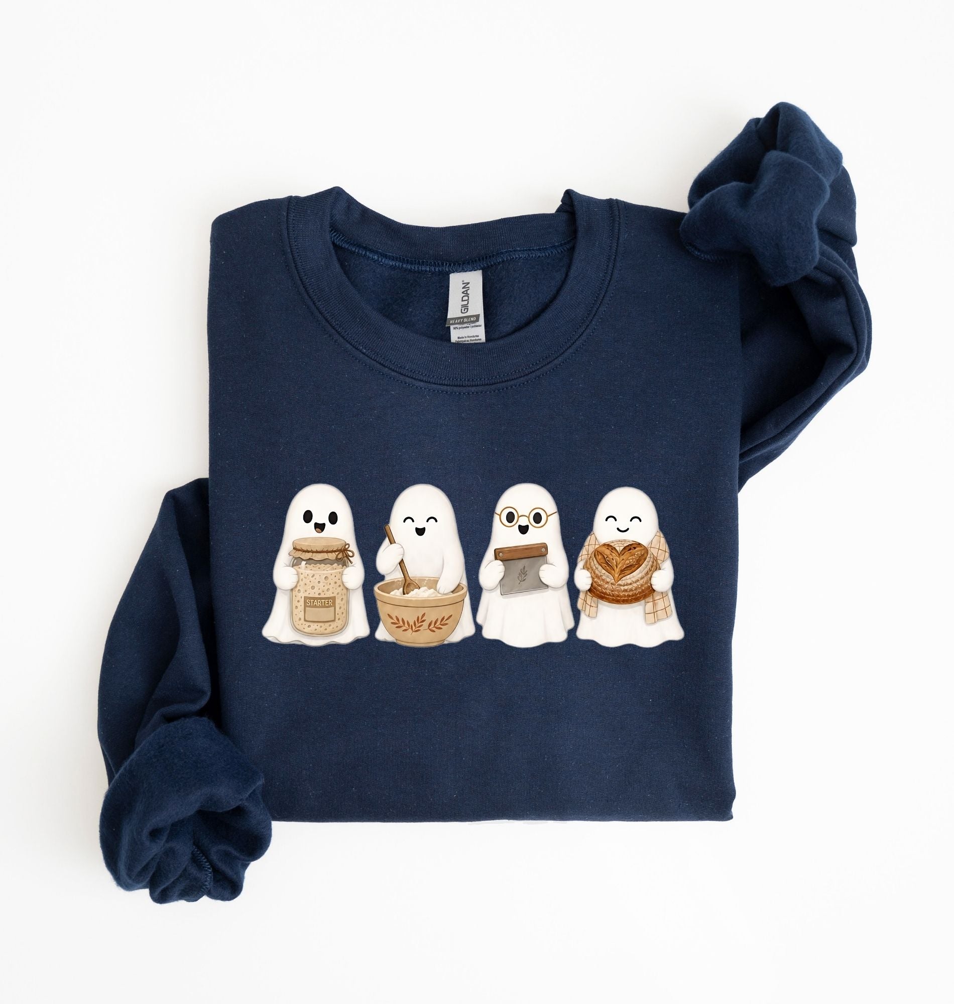 Flat lay of a navy sourdough sweatshirt featuring four cute baking ghosts with a starter jar, mixing bowl, bench scraper and bread loaf on a white background 