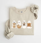 Flat lay of a sand sourdough sweatshirt featuring four cute baking ghosts with a starter jar, mixing bowl, bench scraper and bread loaf on a white background 
