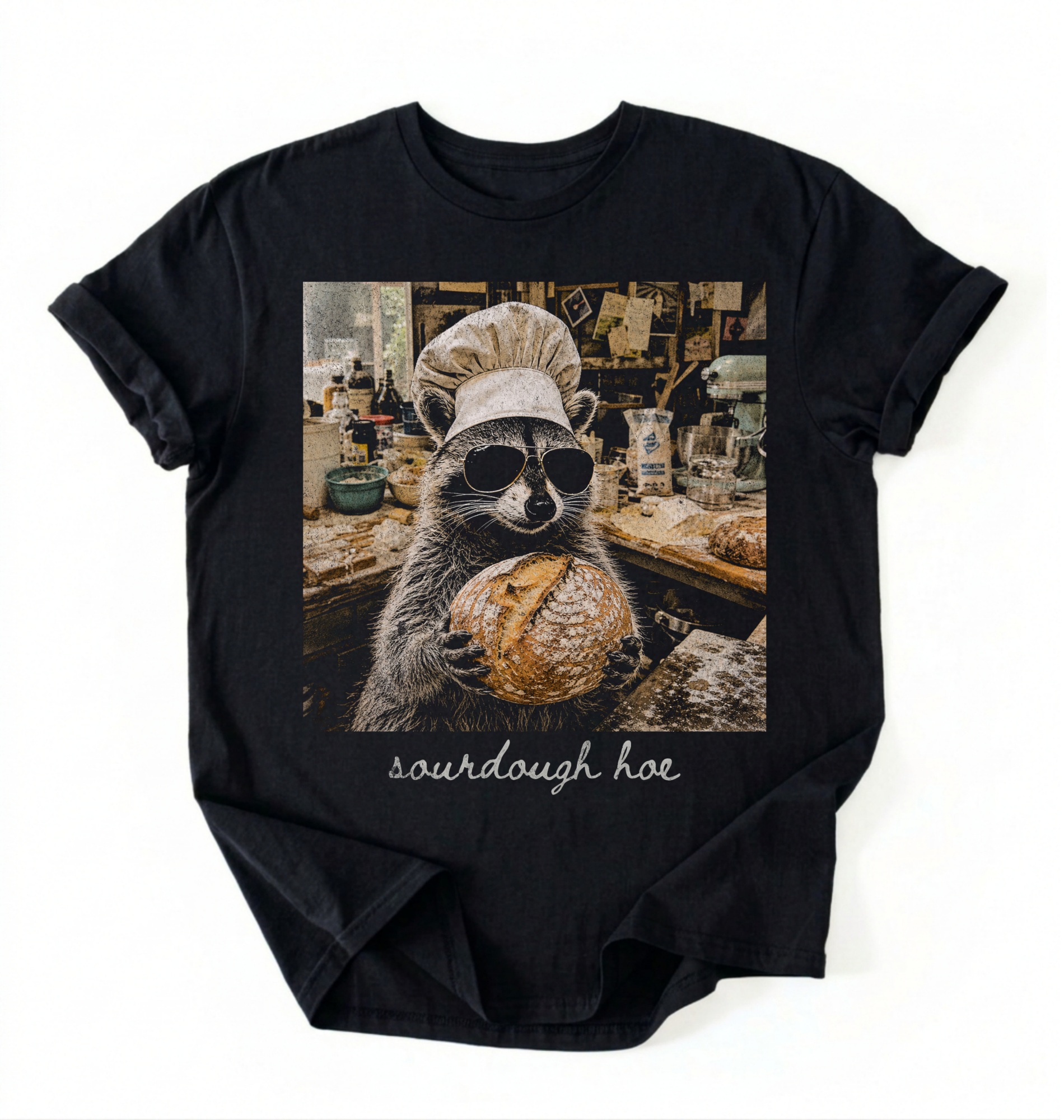 Flat lay of a sourdough hoe shirt black funny raccoon baker t shirt sourdough bread lover gift on a white background 