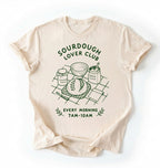 Flat lay of a ivory Sourdough Lover Club graphic shirt with artisan bread baking design for sourdough enthusiasts on a white background 