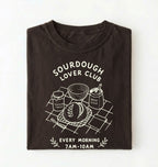 Flat lay of a brown  Sourdough Lover Club graphic shirt with artisan bread baking design for sourdough enthusiasts on a white background 