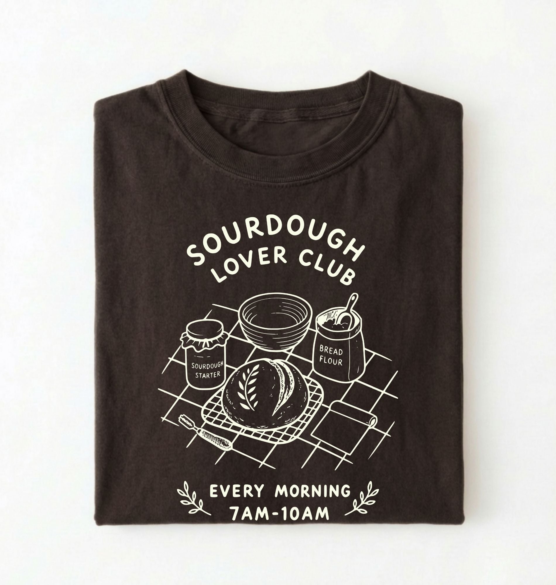 Flat lay of a brown  Sourdough Lover Club graphic shirt with artisan bread baking design for sourdough enthusiasts on a white background 