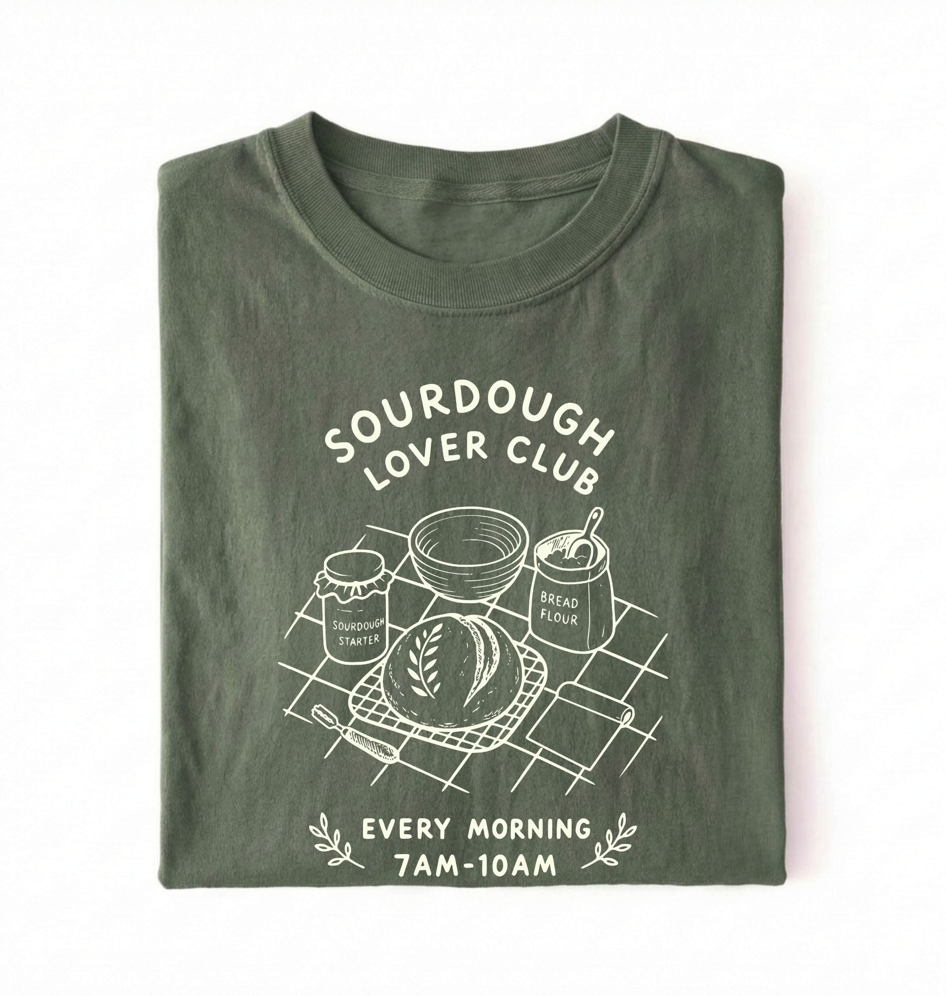 Flat lay of a green Sourdough Lover Club graphic shirt with artisan bread baking design for sourdough enthusiasts on a white background 
