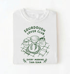 Flat lay of a white Sourdough Lover Club graphic shirt with artisan bread baking design for sourdough enthusiasts on a white background 