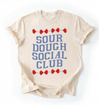 Flat lay of an ivory sourdough social club shirt cream funny baking t shirt bread lover gift cottagecore aesthetic on a white background 