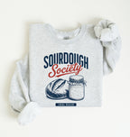 Flat lay of an ash Sourdough Society graphic sweatshirt with artisan bread and sourdough starter jar for bread bakers on a white background 