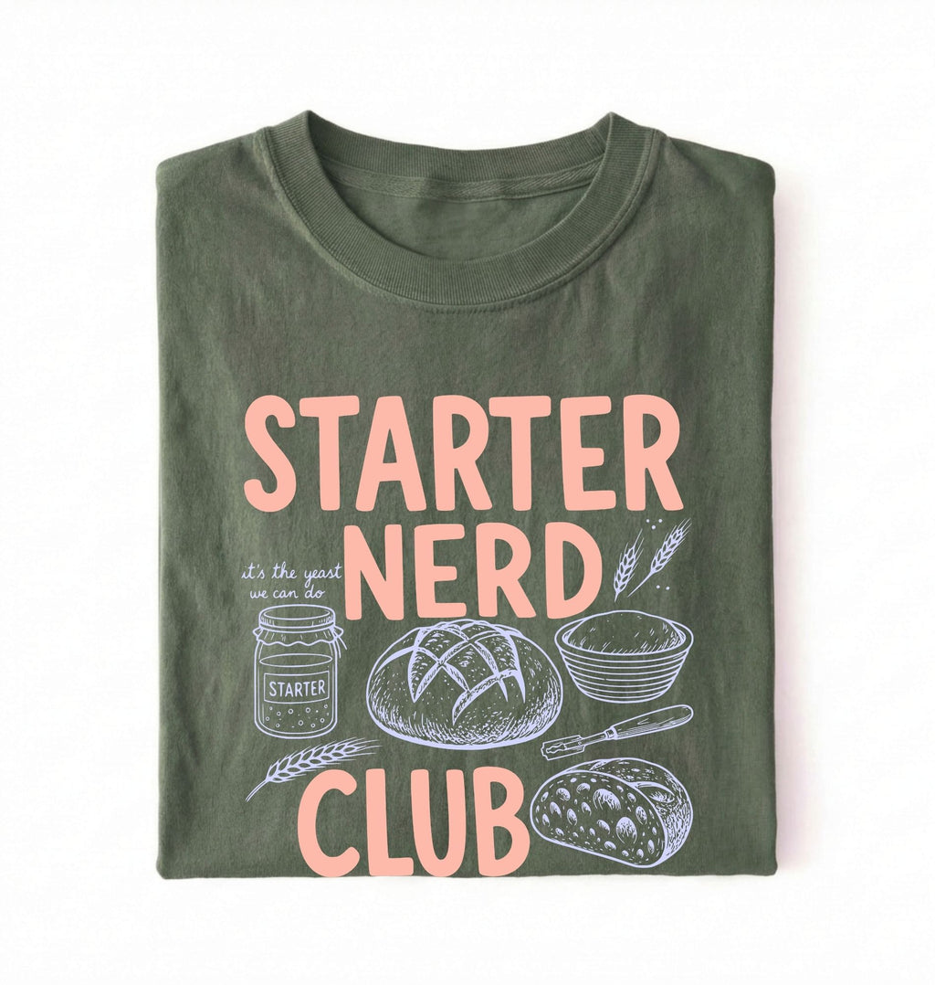 Flat lay of a green starter nerd club shirt with sourdough starter jar bread and baking illustrations funny baker gift on a white background 