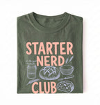 Flat lay of a green starter nerd club shirt with sourdough starter jar bread and baking illustrations funny baker gift on a white background 