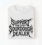 A white short-sleeve crewneck t-shirt with a black graphic print that reads 'SUPPORT YOUR LOCAL SOURDOUGH DEALER' in a stylized, jagged font, displayed flat against a white background.