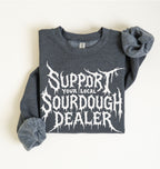 A folded dark heather gray sweatshirt with rolled sleeves, featuring a large white graphic text that reads 'SUPPORT YOUR LOCAL SOURDOUGH DEALER' on a plain off-white background.