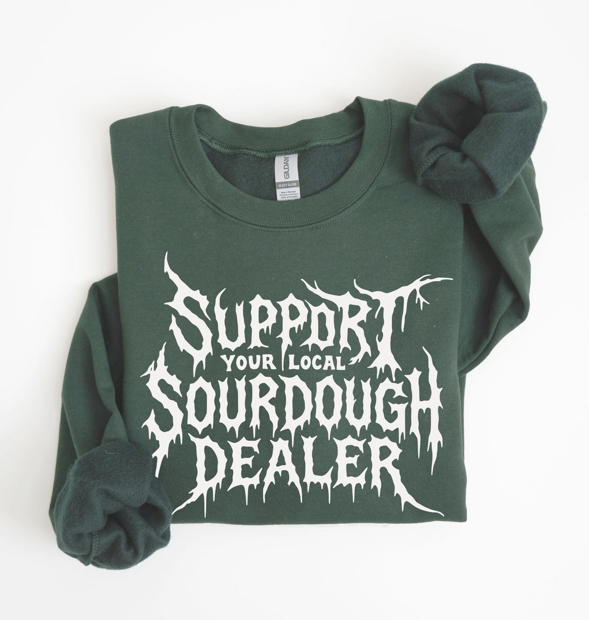 A dark green crewneck sweatshirt with 'Support Your Local Sourdough Dealer' printed in a white, stylized horror font on the front, laid flat on a white background with the sleeves folded.