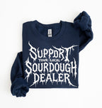 A navy blue sweatshirt with a white graphic print reading 'SUPPORT YOUR LOCAL SOURDOUGH DEALER' in a stylized font, folded neatly on a white background.