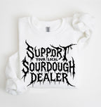 A white long-sleeve sweatshirt laid flat on a white background, featuring a large black distressed graphic that reads 'SUPPORT YOUR LOCAL SOURDOUGH DEALER' across the front.