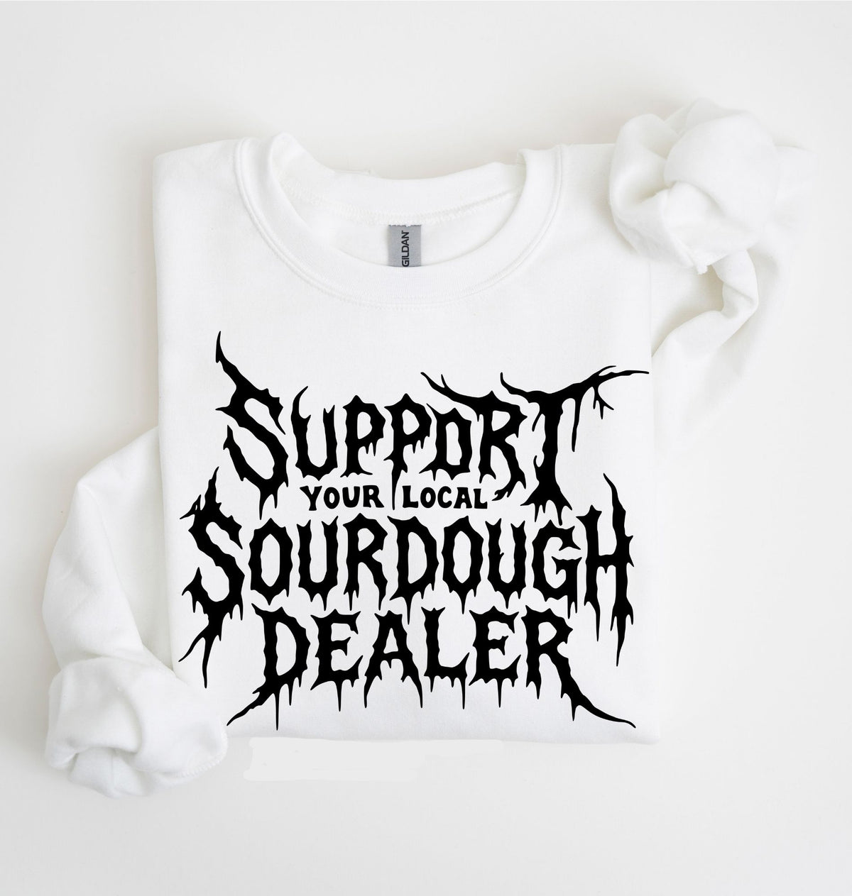 A white long-sleeve sweatshirt laid flat on a white background, featuring a large black distressed graphic that reads 'SUPPORT YOUR LOCAL SOURDOUGH DEALER' across the front.