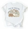 Flat lay of an white take me thrifting shirt cream vintage thrift store t shirt cottagecore antique gift on a white background 