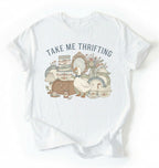 Flat lay of an white take me thrifting shirt cream vintage thrift store t shirt cottagecore antique gift on a white background 